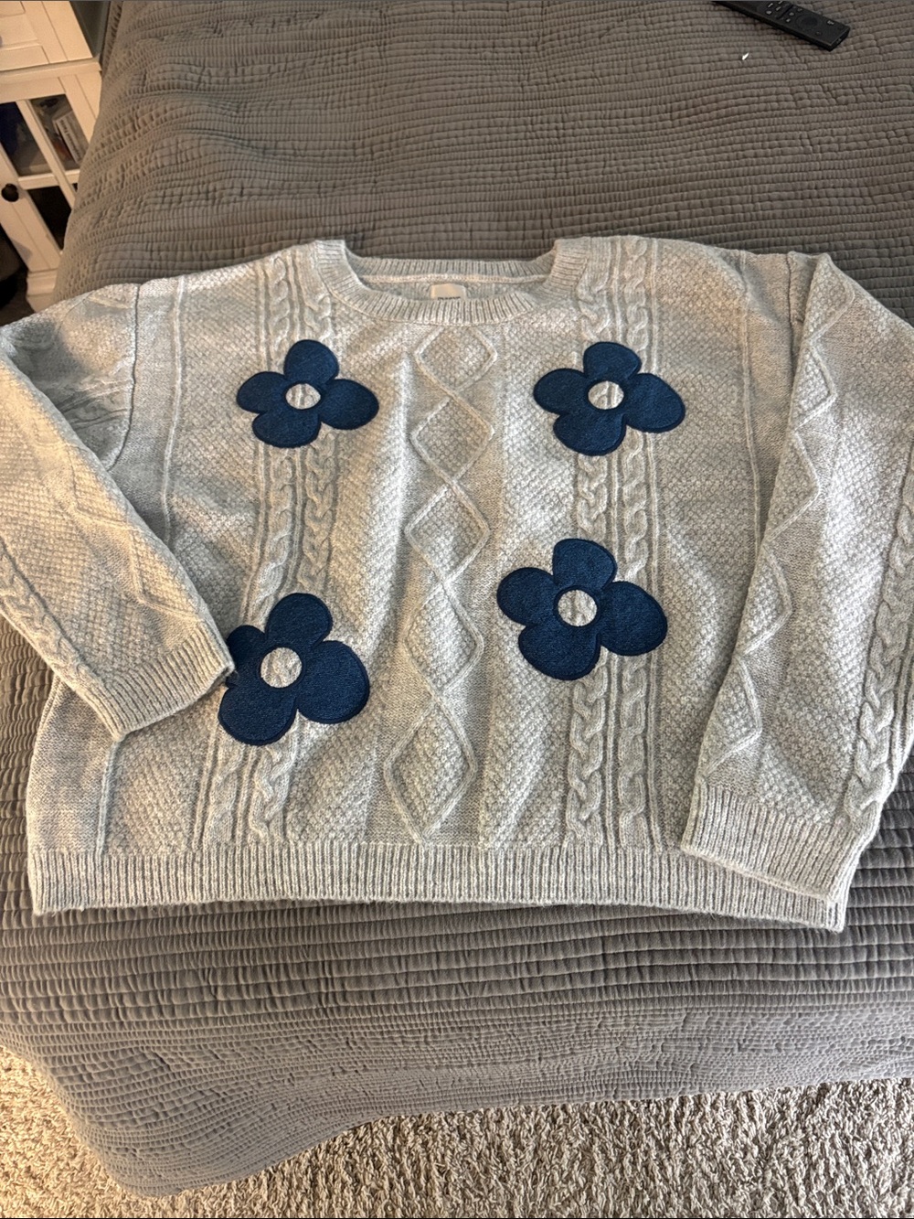 Anthropologie Light Gray Cable-Knit Sweater with Navy Flower Appliqués.